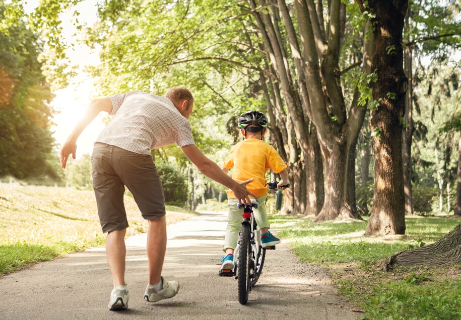 man teaching boy to ride bike